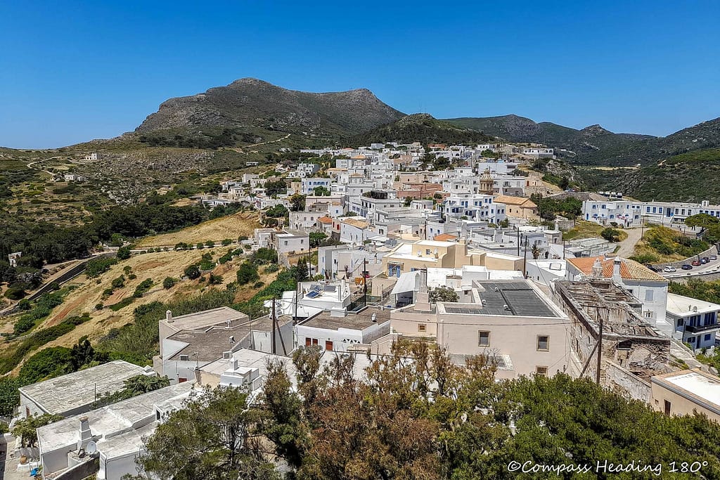 The Chora town is a very thick carpet of white and pastel coloured houses with flat roofs. Around the town, there are olive groves and hills in the distance.