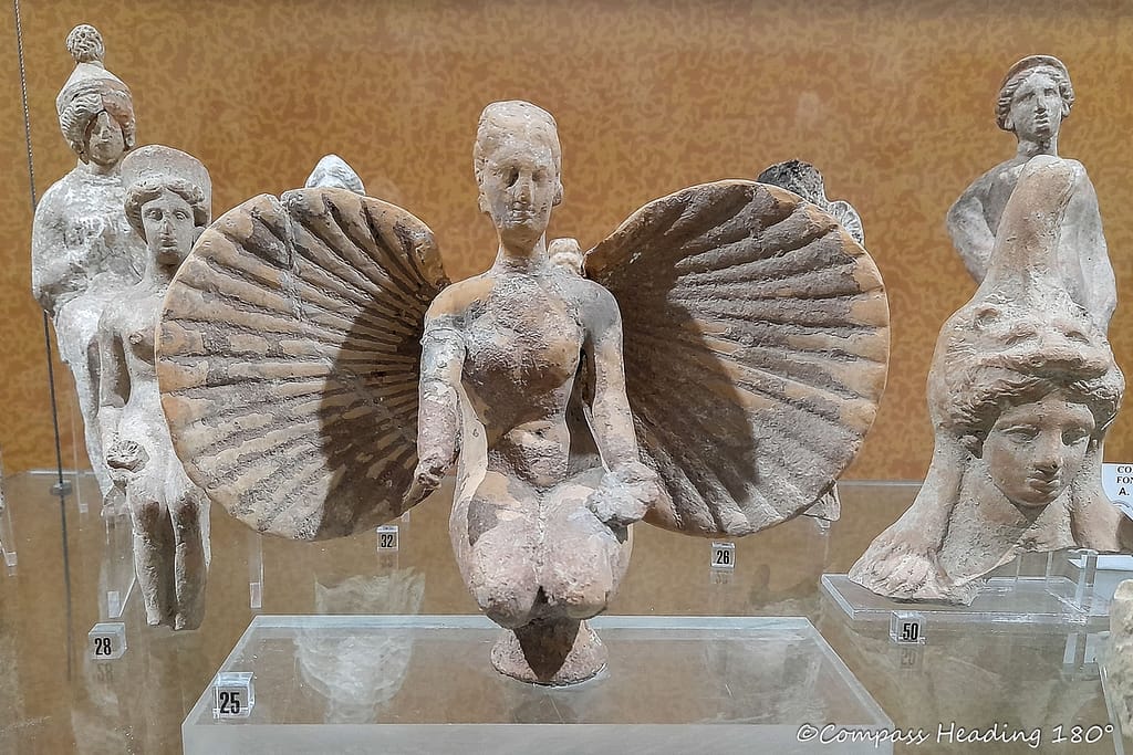 Pieni kaunis antiikkinen patsas esittää naishahmoa, jolla on kampasimpukan muotoiset siivet