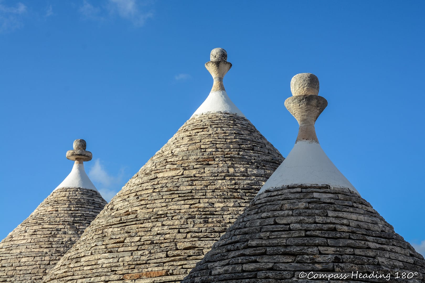 Trullotalojen kartiomaisia kivestä ladottuja kattoja, joiden huipulla on pyöreät koristepallot