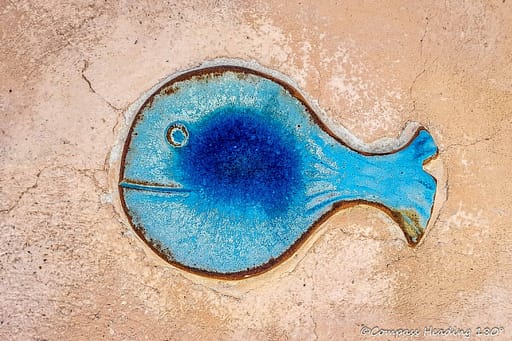 A blue fish shaped ceramic tile from a house facade.